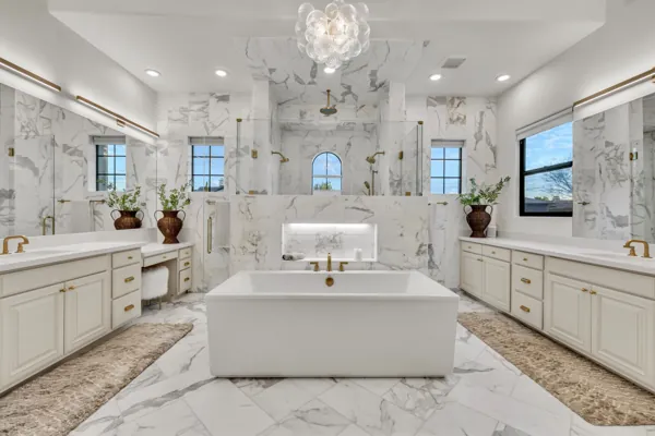 Luxury real estate photography showcasing a stunning marble bathroom in Gilbert, AZ, featuring a central soaking tub, dual vanities, and elegant fixtures.