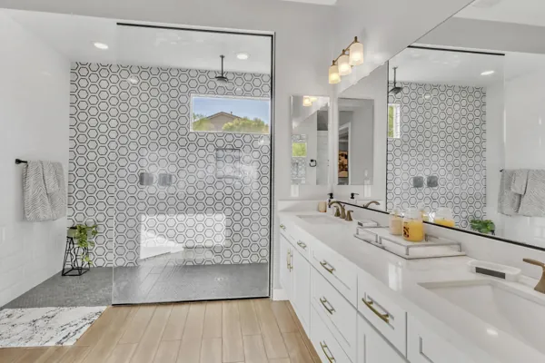 This modern bathroom in Phoenix, AZ features a double vanity and glass shower with stylish geometric tile, perfect for real estate photography showcasing elegant home design.