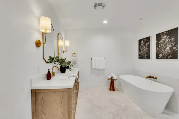 This bright modern bathroom in Phoenix, AZ features a freestanding tub, wood cabinet vanity, and elegant lighting, captured with professional real estate photography.