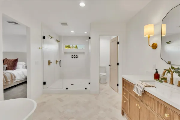 This modern bathroom in Phoenix, AZ features a spacious shower, elegant vanity, and clean design, captured with professional real estate photography to highlight its stylish and functional elements.