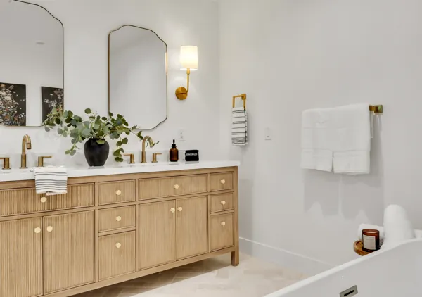 This modern bathroom in Phoenix, AZ features a double sink vanity with gold fixtures, elegant mirrors, and a clean, stylish design highlighted by professional real estate photography.
