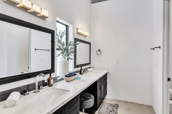 This modern bathroom in Scottsdale, AZ features a double vanity with black cabinetry and sleek fixtures, captured with professional real estate photography to highlight its stylish design and spacious layout.