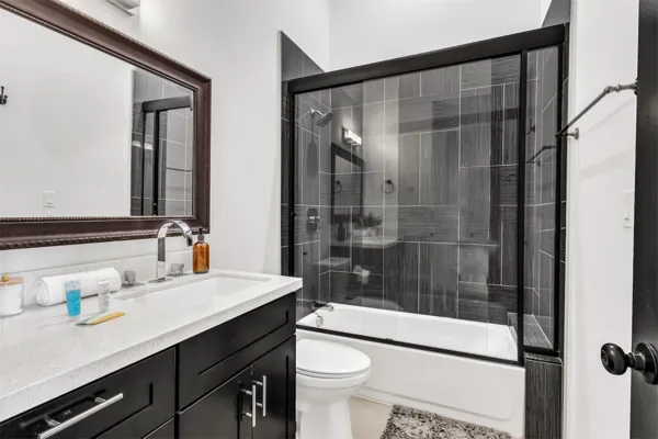 This modern bathroom in Scottsdale, AZ features a black vanity with white countertop and a glass shower enclosure, perfectly captured with professional real estate photography.