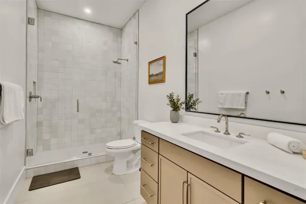 This modern bathroom in Scottsdale, AZ features a glass-enclosed shower, neutral cabinetry, and elegant real estate photography showcasing a clean and stylish design.