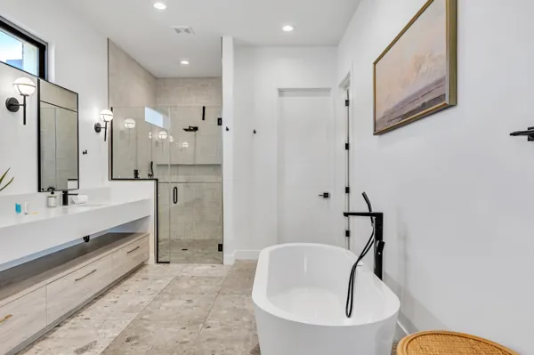 This modern bathroom in Scottsdale, AZ features a freestanding tub, glass shower, and sleek vanity, captured with professional real estate photography to highlight its contemporary design and spacious layout.