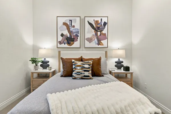 This real estate photography showcases a cozy bedroom in Mesa, AZ, featuring modern art and stylish lamps, highlighting the home's inviting atmosphere.