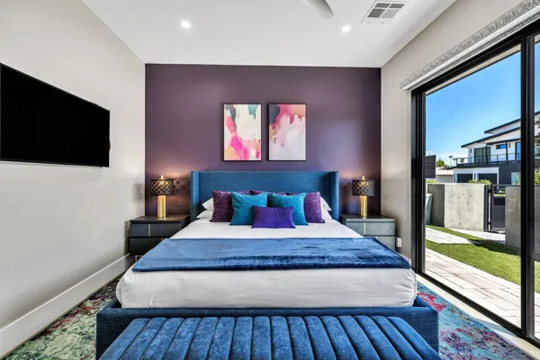 This modern bedroom in Scottsdale, AZ features vibrant decor and a large sliding door leading to an outdoor space, captured with professional real estate photography.