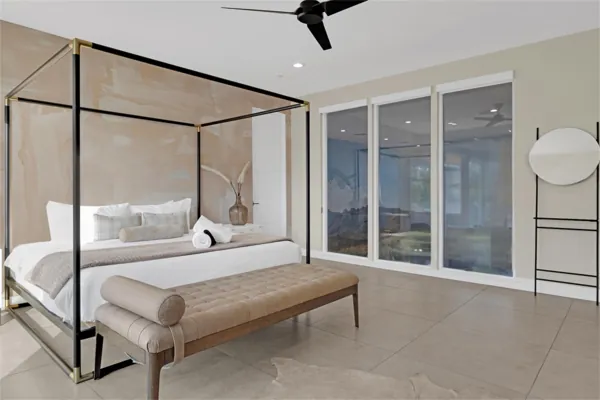 This modern bedroom in Scottsdale, AZ features a stylish four-poster bed and large windows, captured with expert real estate photography to highlight the room's spacious and elegant design.