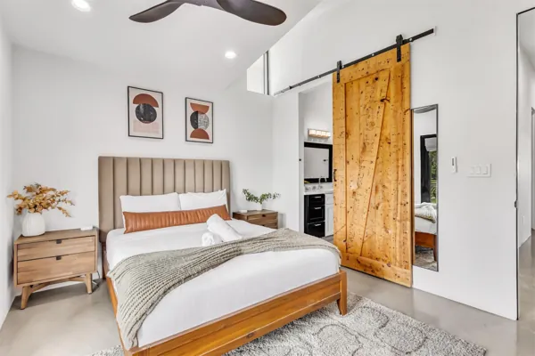 This modern bedroom in Scottsdale, AZ features a stylish wooden sliding door and contemporary furnishings, captured through professional real estate photography.