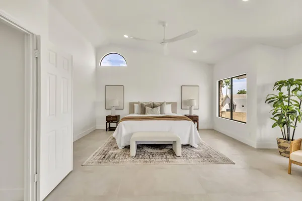 This minimalist bedroom in Scottsdale, AZ features high ceilings, large windows, and tasteful decor, captured with professional real estate photography to highlight its spacious and bright design.