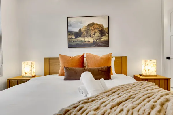 This Scottsdale, AZ bedroom features a modern design with bright orange pillows, soft lighting, and cozy decor, captured beautifully in real estate photography.