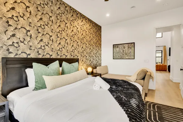 This modern bedroom in Scottsdale, AZ features a striking floral accent wall and cozy furnishings captured through expert real estate photography.