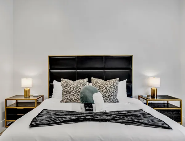 This modern bedroom in Scottsdale, AZ features a stylish black headboard, chic nightstands, and decorative pillows, showcasing elegant real estate photography that highlights the room's contemporary design and comfort.