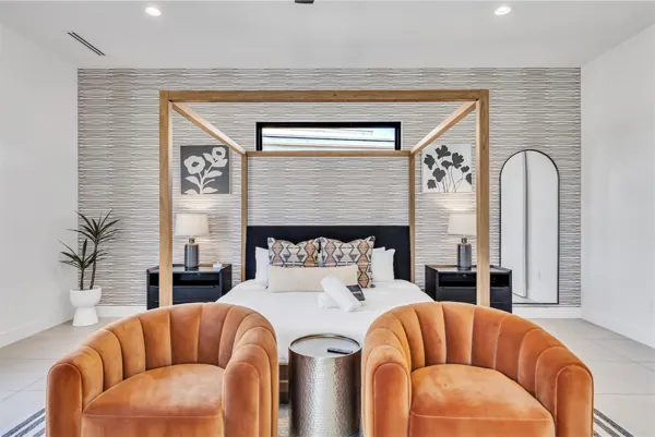 This modern bedroom in Scottsdale, AZ features a canopy bed with artistic decor and cozy seating, captured through expert real estate photography.