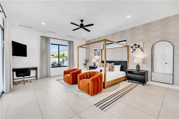 This modern bedroom in Scottsdale, AZ features a four-poster bed, cozy seating, and an office space, captured with high-quality real estate photography perfect for showcasing stylish home interiors.