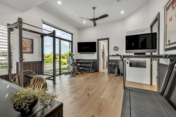 Discover luxury real estate photography showcasing a modern home gym with large windows in Gilbert, AZ, offering an exquisite view and premium equipment.