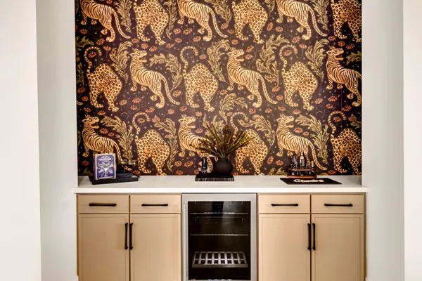 This stylish bar area in Scottsdale, AZ features a built-in wine fridge and vibrant wildlife wallpaper, captured expertly for real estate photography showcasing unique interior design.