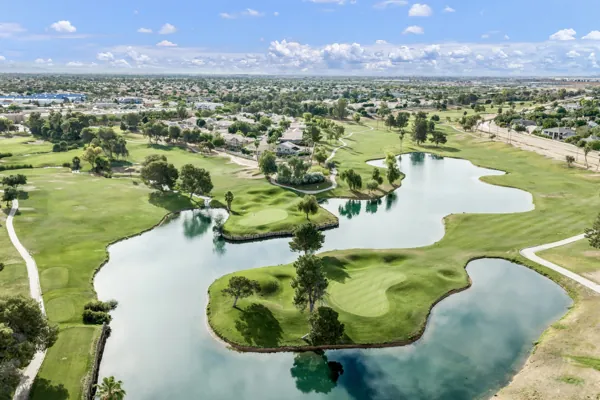 Aerial real estate photography showcasing a golf course with lush greens and water features in Gilbert, AZ, highlighting the scenic and tranquil surroundings ideal for homebuyers.