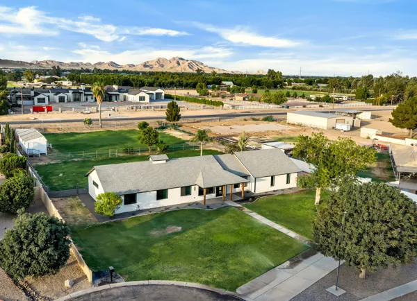 This aerial exterior real estate photography showcases a spacious Mesa, AZ home with a large yard and mountain views, ideal for buyers seeking a peaceful neighborhood.