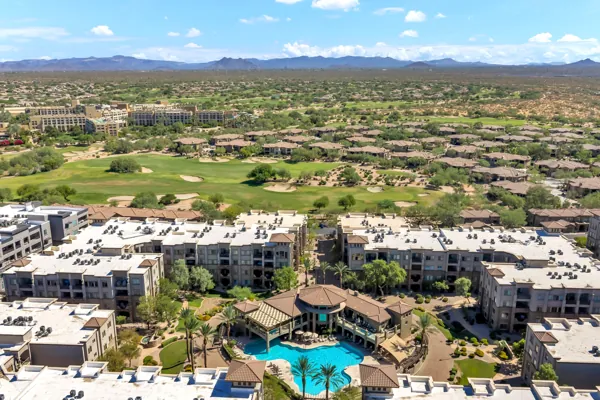 This stunning aerial real estate photography showcases a Phoenix, AZ apartment complex with a large pool and nearby golf course, highlighting luxurious living and scenic mountain views.
