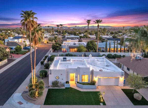 This stunning twilight aerial view showcases a charming Scottsdale, AZ home with beautifully lit exterior and manicured landscaping, perfect for real estate photography.
