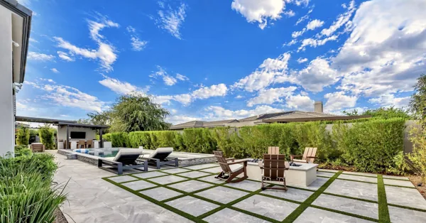 This luxury real estate photography showcases a stunning outdoor space in Gilbert, AZ, featuring a pool, patio seating, and lush greenery.