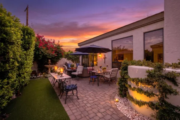 Beautiful outdoor patio with dining furniture and lush landscaping at sunset, captured in Scottsdale, AZ real estate photography showcasing inviting exterior living space.