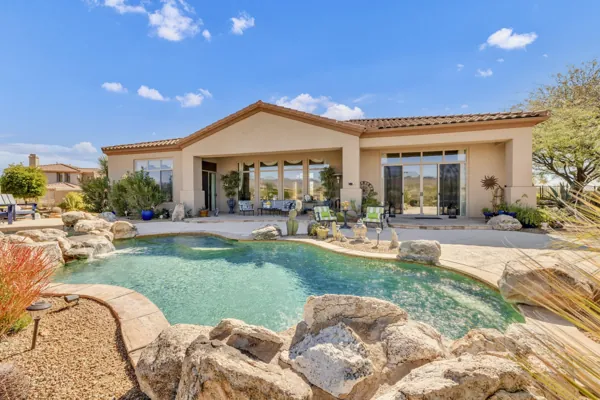 Beautiful backyard with pool, rocks, and patio featuring outdoor seating in Scottsdale, AZ, captured with professional real estate photography.