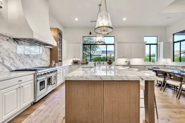 This luxury real estate photography showcases a stunning modern kitchen in Gilbert, AZ, featuring a spacious marble island and elegant pendant lighting.
