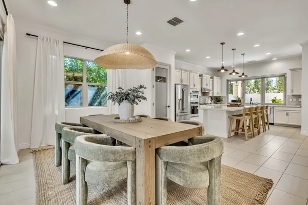 Explore the elegant kitchen and dining space in this real estate photography in Mesa, AZ, showcasing sleek cabinetry, a large island, and natural lighting.