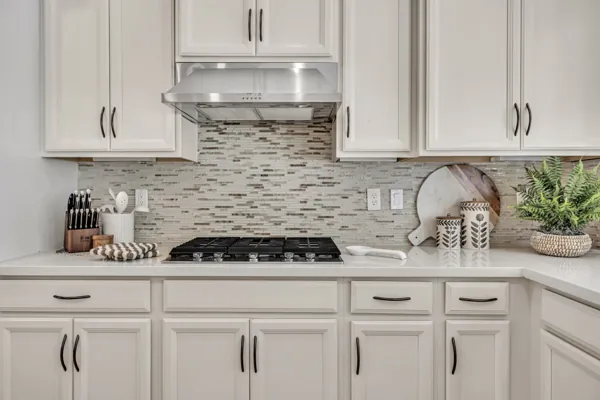 This real estate photography showcases a modern kitchen in Mesa, AZ with elegant white cabinets and a sleek backsplash.