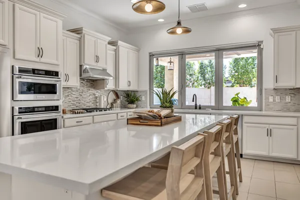 This modern kitchen in Mesa, AZ, features sleek white cabinets and a spacious island, showcasing professional real estate photography.