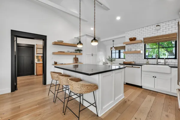 This luxury real estate photography showcases a modern kitchen on E Avalon Dr, Phoenix, AZ, featuring white cabinets, a large island, and elegant finishes.