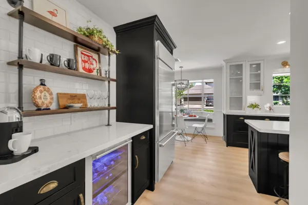 This modern kitchen in Phoenix, AZ features black cabinetry, stainless steel appliances, and bright natural lighting, professionally captured with expert real estate photography to showcase its stylish design.
