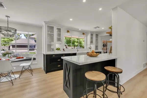 This modern kitchen in Phoenix, AZ features a spacious island, large windows, and a cozy dining nook, showcasing expert real estate photography that highlights its bright and inviting design.