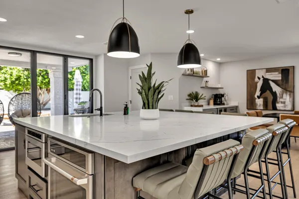 This real estate photography captures a modern kitchen in Scottsdale, AZ, showcasing a spacious island with sleek design and stylish seating.