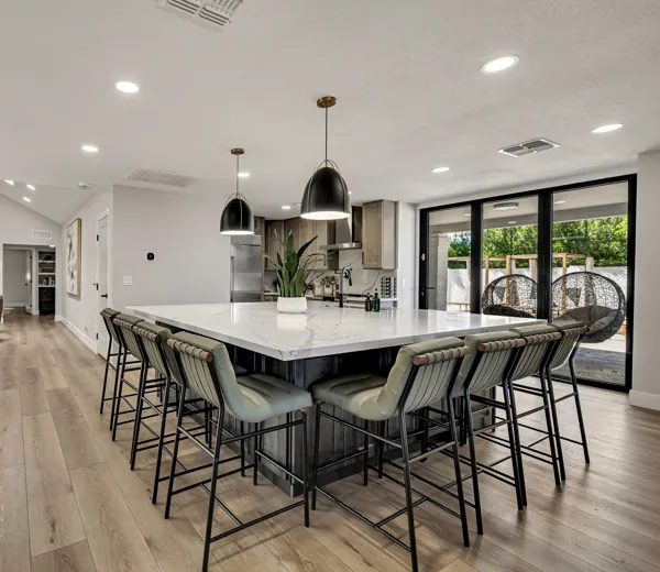 This real estate photography showcases a modern kitchen in Scottsdale, AZ, featuring a spacious island and elegant bar stools, perfect for entertainment and family gatherings.