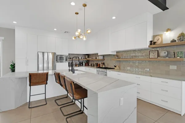 This modern kitchen in Scottsdale, AZ features a white island with leather stools and sleek cabinetry, captured with expert real estate photography to highlight its spacious and stylish design.