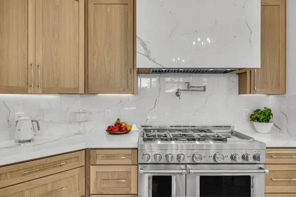 This real estate photography showcases a modern kitchen in Scottsdale, AZ, featuring elegant wood cabinetry and a sleek marble backsplash, perfect for any luxurious home.