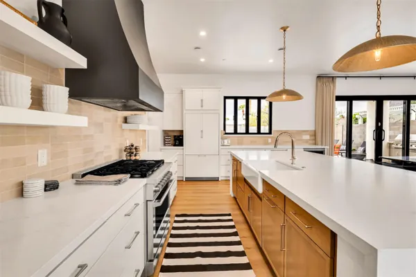 This modern kitchen in Scottsdale, AZ features a spacious island with dual sinks, stainless steel appliances, and elegant lighting, captured perfectly by expert real estate photography.