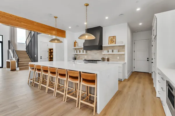 This Scottsdale, AZ kitchen features a modern island with barstools, wood flooring, and pendant lighting, captured with expert real estate photography to highlight its spacious and stylish design.