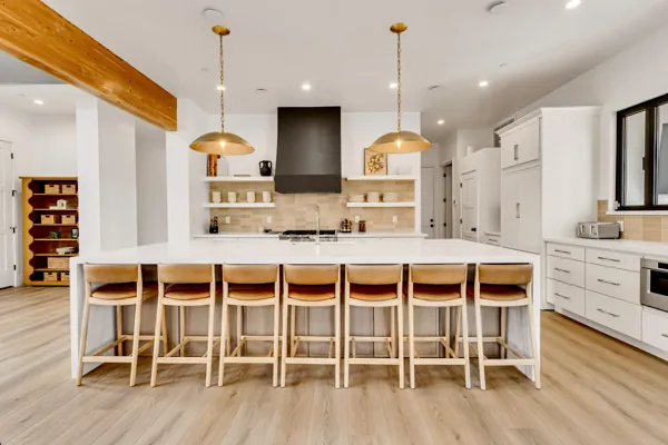 This modern kitchen in Scottsdale, AZ features a large island with leather stools and sleek cabinetry, beautifully captured in real estate photography to highlight the spacious and stylish design.