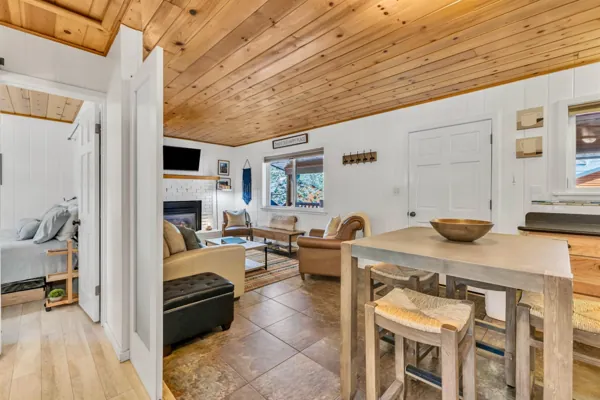 This cozy living room and dining area feature a wooden ceiling and modern fireplace in a Greer, AZ home, captured with expert real estate photography to showcase warmth and comfort.