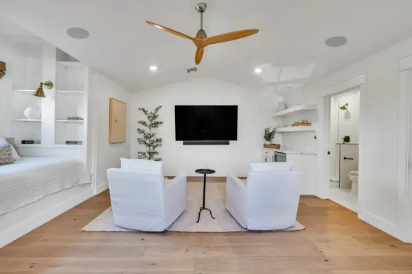 This luxury real estate photography showcases a modern living room in Phoenix, AZ, with elegant white chairs and a flat-screen TV.