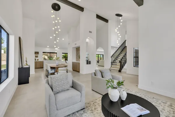 Spacious modern living room and dining area with staircase in a Scottsdale, AZ home, captured with professional real estate photography highlighting bright interiors and contemporary design.