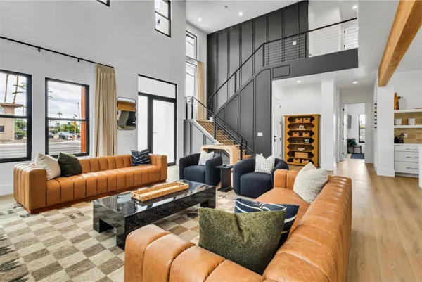 This modern living room features stylish leather sofas and a striking staircase, showcasing elegant real estate photography in Scottsdale, AZ.