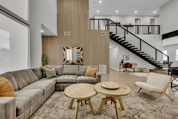 This modern living room in Scottsdale, AZ is perfect for an Airbnb photo shoot, featuring a stylish sofa and elegant staircase.