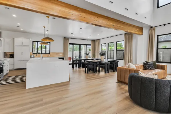 This open-concept kitchen, dining, and living area in Scottsdale, AZ, features modern design with wood accents and ample natural light, captured with expert real estate photography.