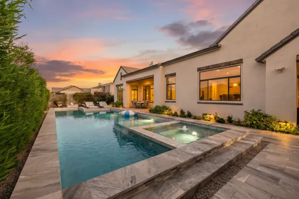 This luxury real estate photography showcases a stunning backyard pool at sunset in Gilbert, AZ, highlighting the exquisite design and serene atmosphere.