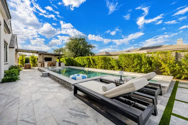 Experience luxury real estate photography with this stunning outdoor view in Gilbert, AZ, showcasing a sleek poolside patio with modern lounge chairs.